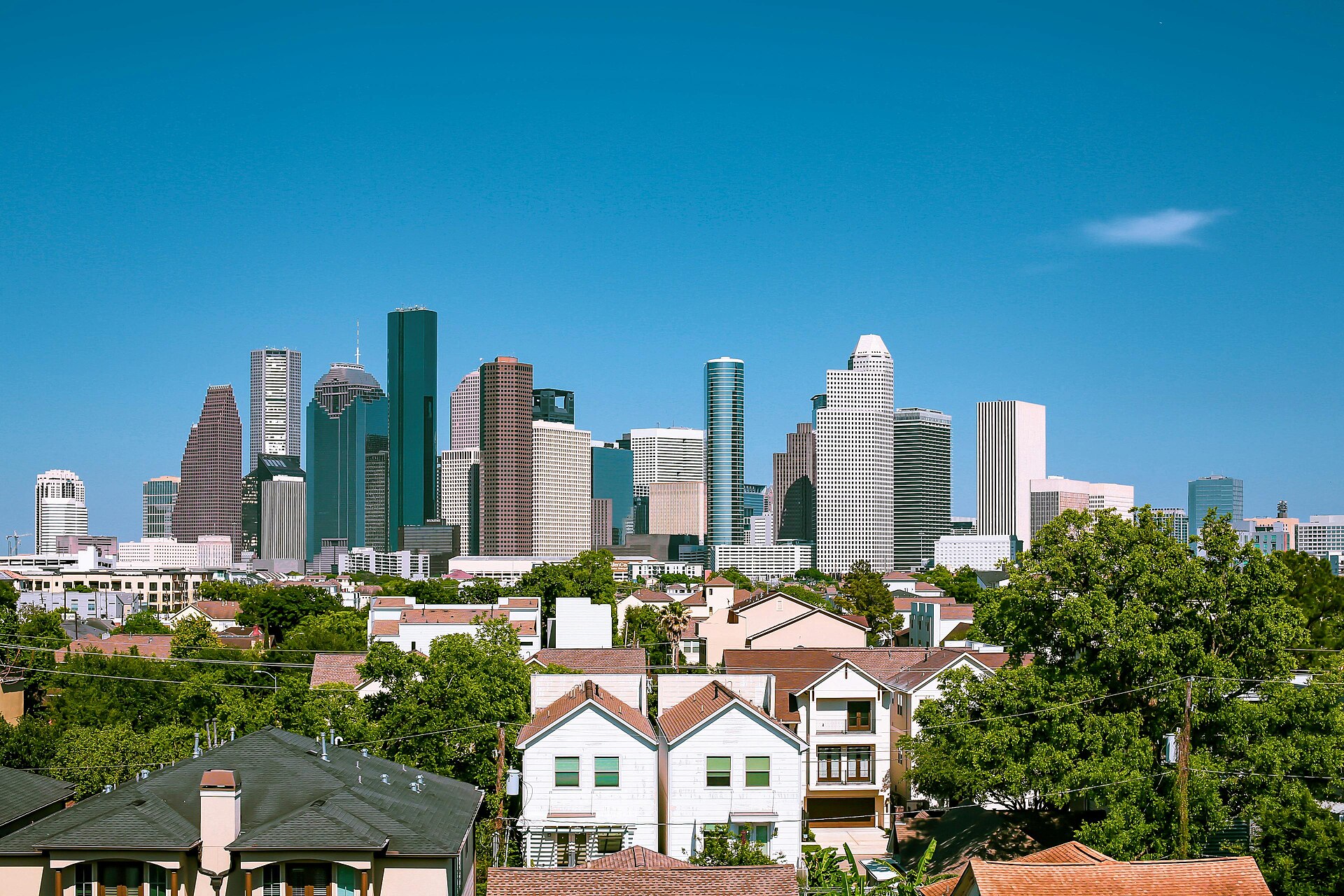 Downtown Houston skyline rising above residential rooftops and trees