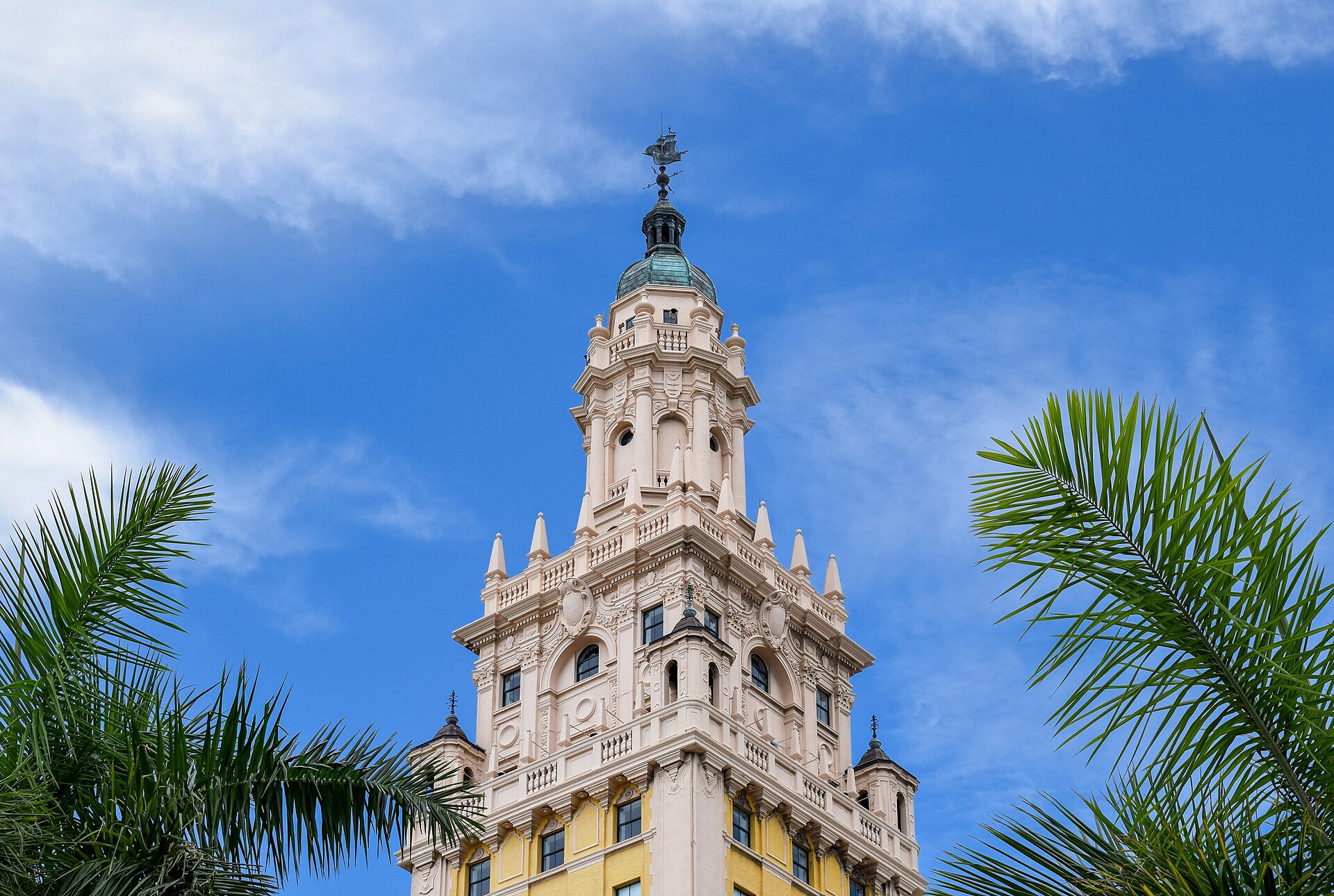 Ornate top of Miami's Freedom Tower framed by palm fronds