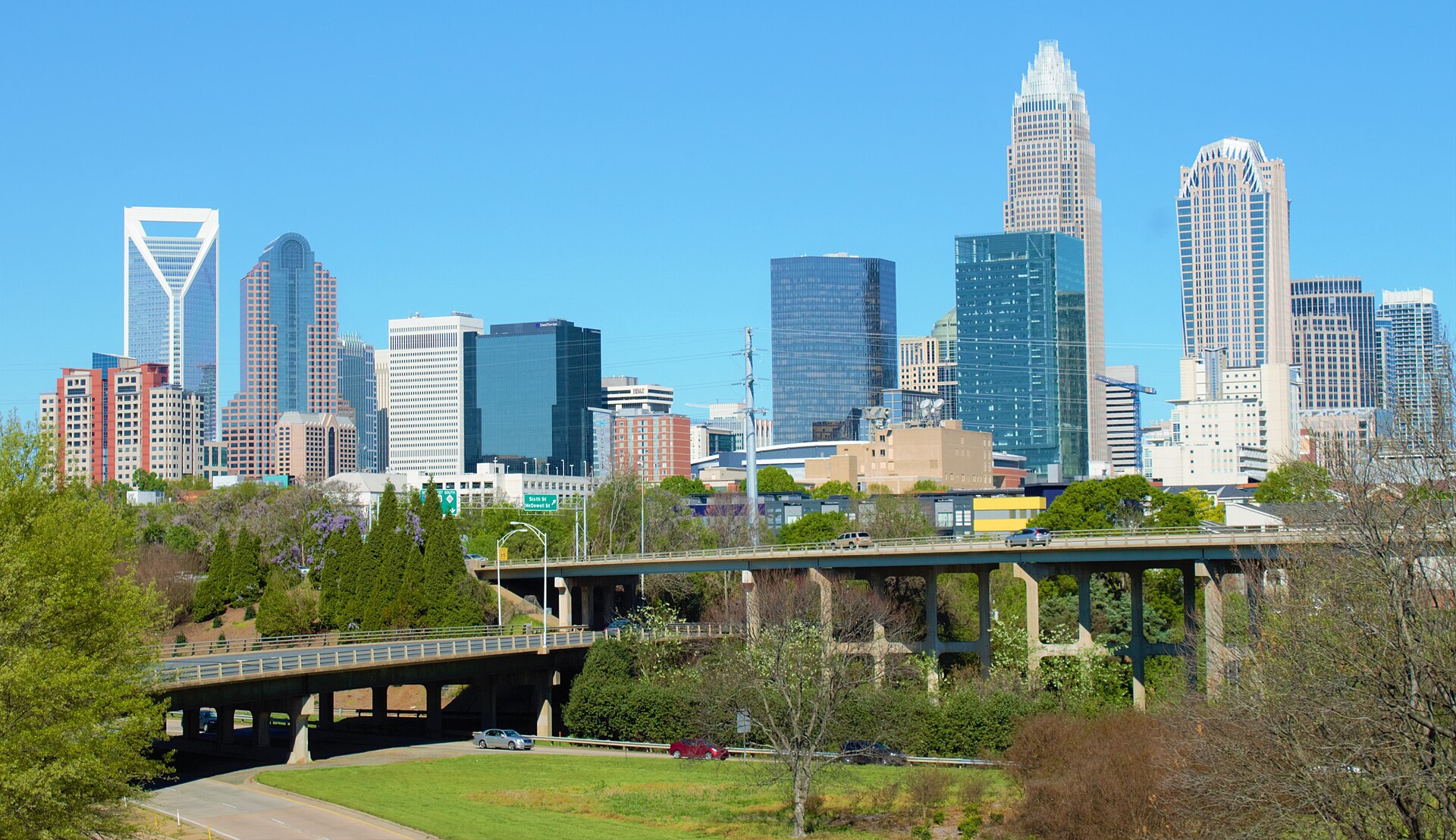 Uptown Charlotte skyline above highway bridges and spring trees